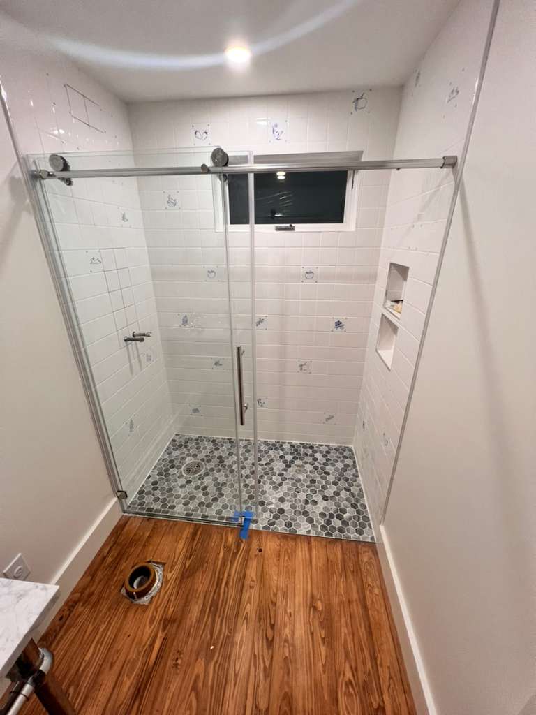 Walk-in shower with subway tile and mosaic floor during finish work