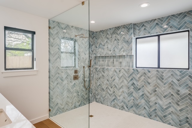 Modern walk-in shower with herringbone tile and brass fixtures
